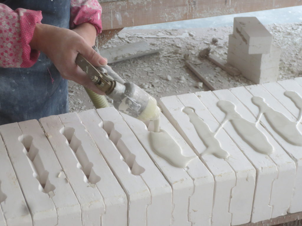 liquid clay (Slip) being injected into block moulds for cup handles